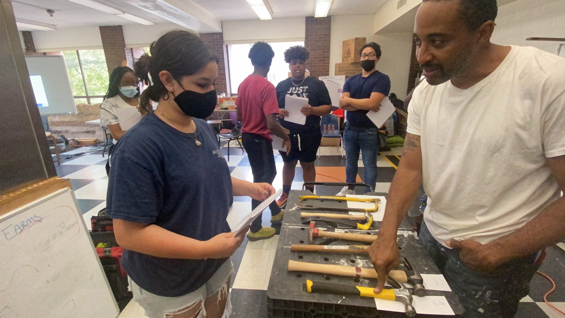 Trainees reviewing hand tools at a BTW workstation