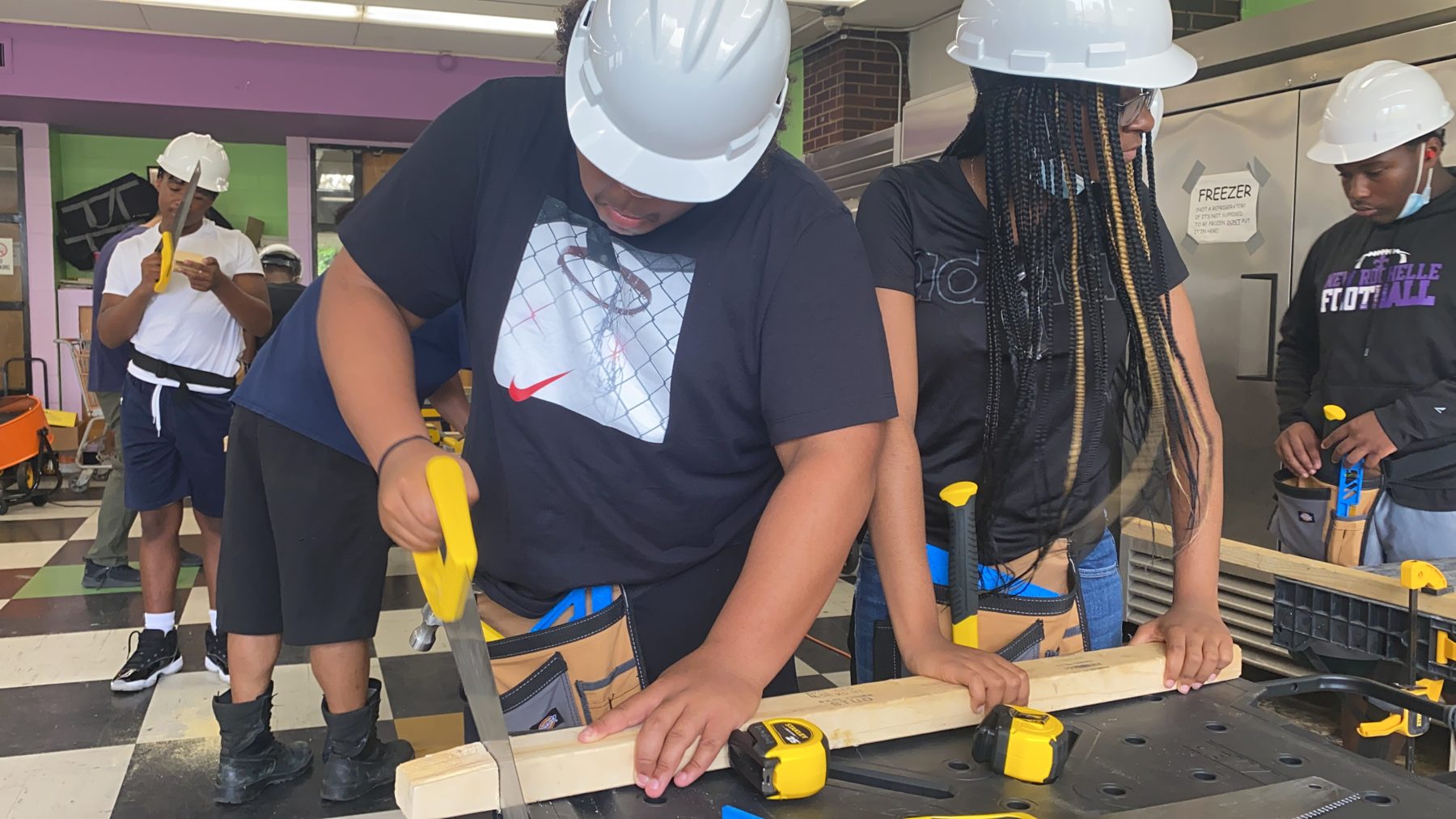 A BTW trainee guiding a cut on a workbench while classmates observe