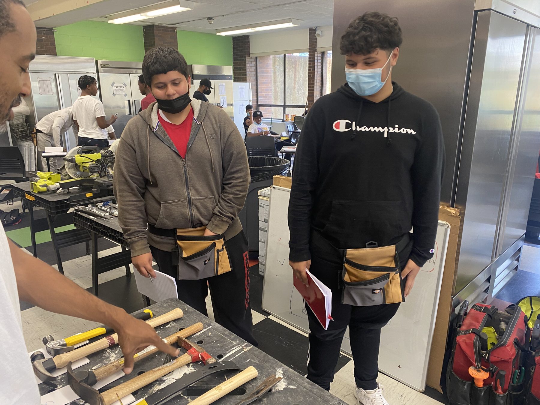 A BTW instructor coaching two students at a tool bench